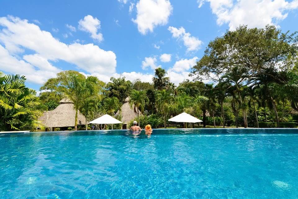 Two people relaxing in the swimming pool overlooking the jungle