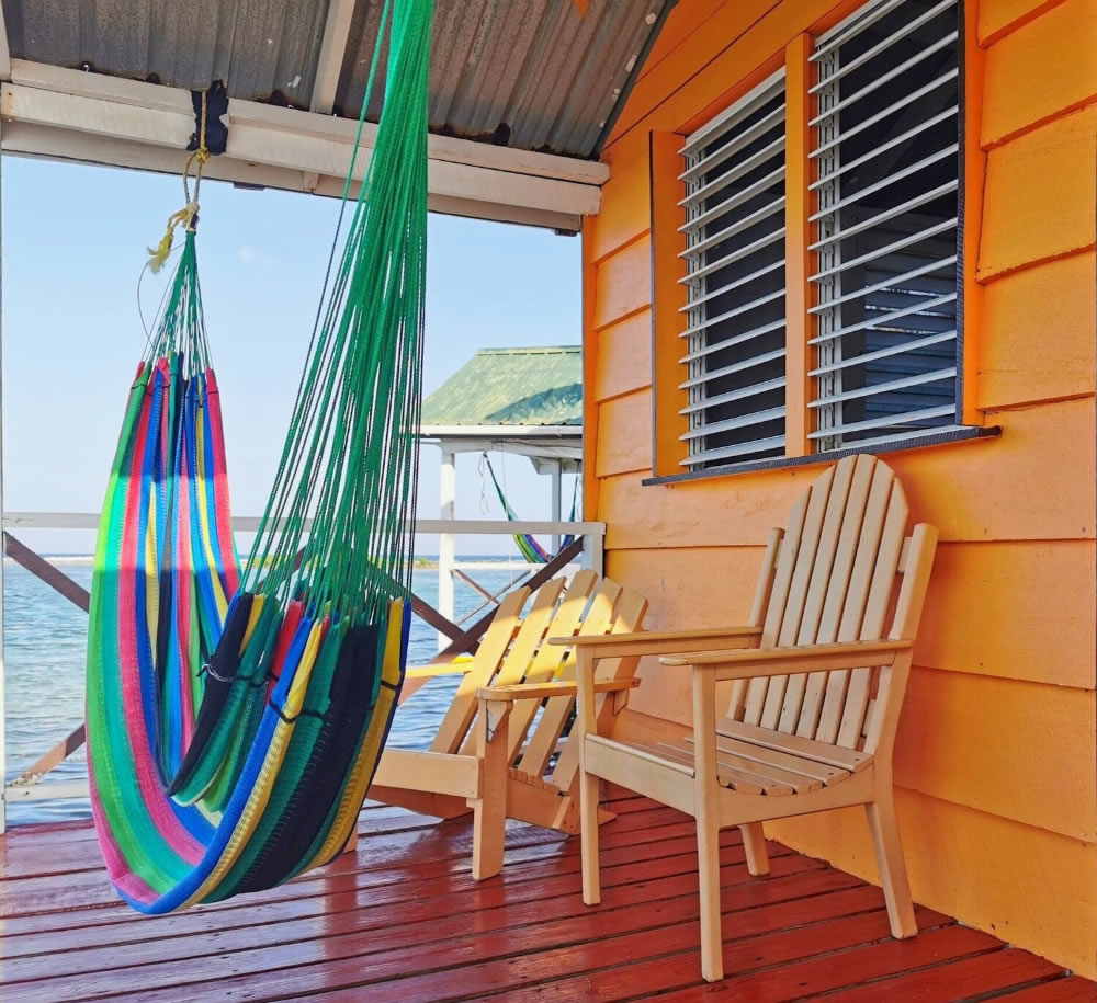 A hammock hanging on the deck of a orange color overwater cabin