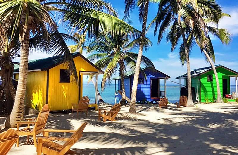The rear of three overwater cabins, one yellow, one blue and one green