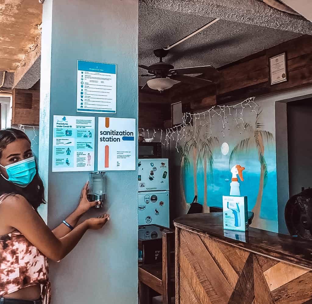 Lobby front desk with clerk wearing a mask and getting hand sanitizer