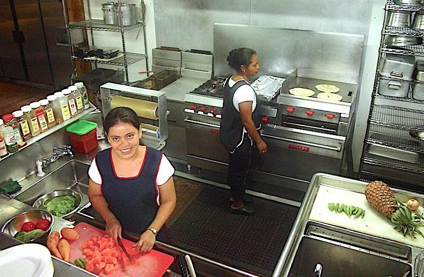 Two female cooks preparing meals in Lamanai Outpost Lodge kitchen