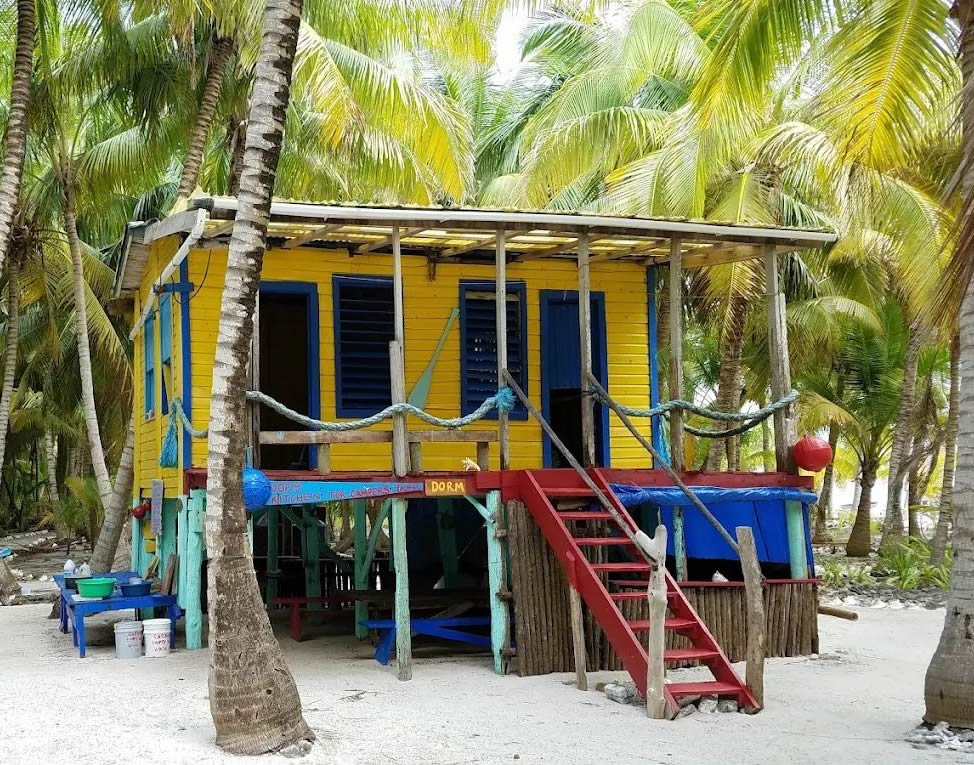 Exterior of a rustic yellow painted dormitory on stilts
