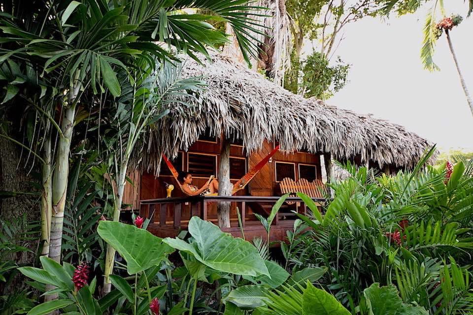 Woman reading in a hammock on porch of Lamanai Family cabana