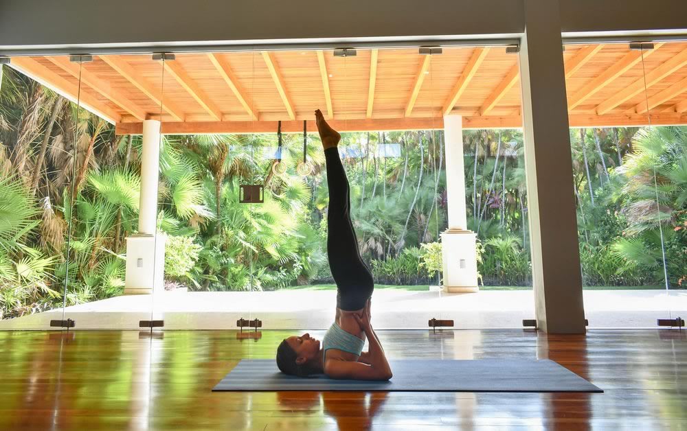 Woman doing yoga under a private thatched roof shed