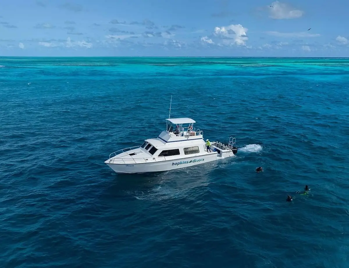 Dive boat with divers in the water at Glover's Reef